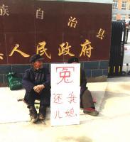 Frau Cuis Schwiegereltern bitten mit dem Schild um ihre Freilassung. Foto: de.minghui.org