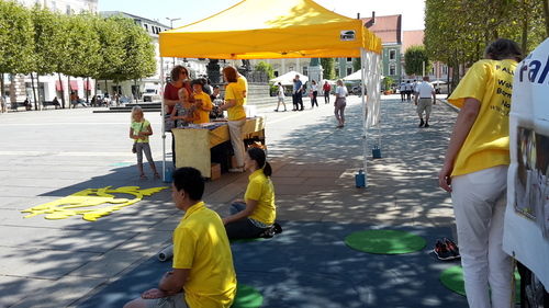 Passanten beim Informationsstand. Das Mädchen schaut neurierig den Meditierenden zu. 