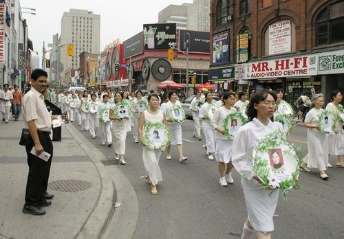 Praktizierende trugen in Toronto am 17. Juli zum Gedenken Fotos von Todesopfern der Verfolgung. © FDI