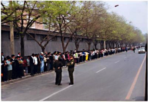 Falun-Dafa-Praktizierende warten am 25. April 1999 in Peking an von den Sicherheitskräften zugewiesenen Stellen.