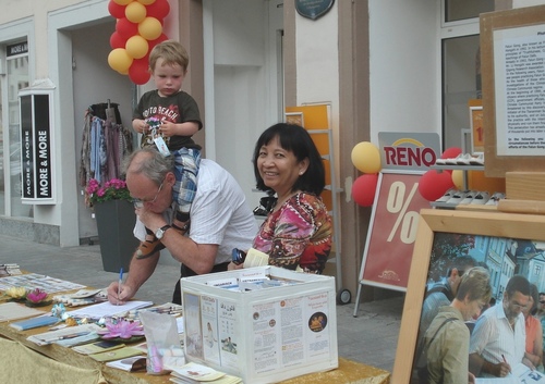 Viele Passanten, die die wahren Umstände der Verfolgung der Falun Gong-Praktizierenden erfahren hatten, unterschreiben bereitwillig die aufliegenden Petitionen